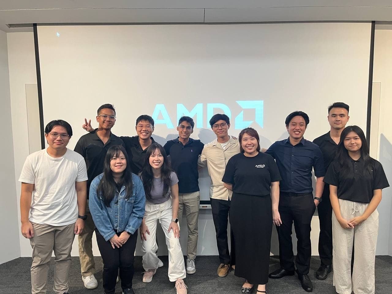 Club members and AMD speakers in front of an illuminated AMD logo