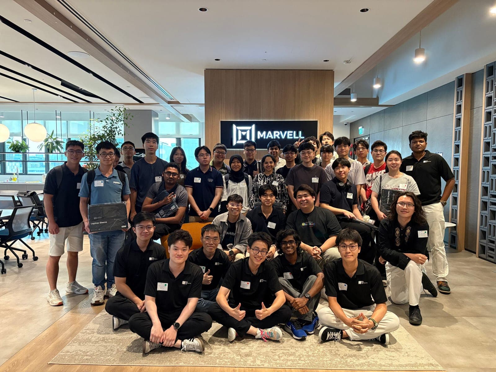 The visiting group photographed together beneath the Marvell sign in the company's Singapore office